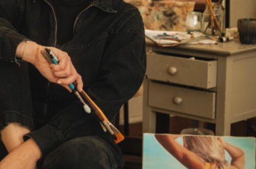 Une artiste peintre, jeune et dynamique, posant devant une de ses toiles dans son atelier