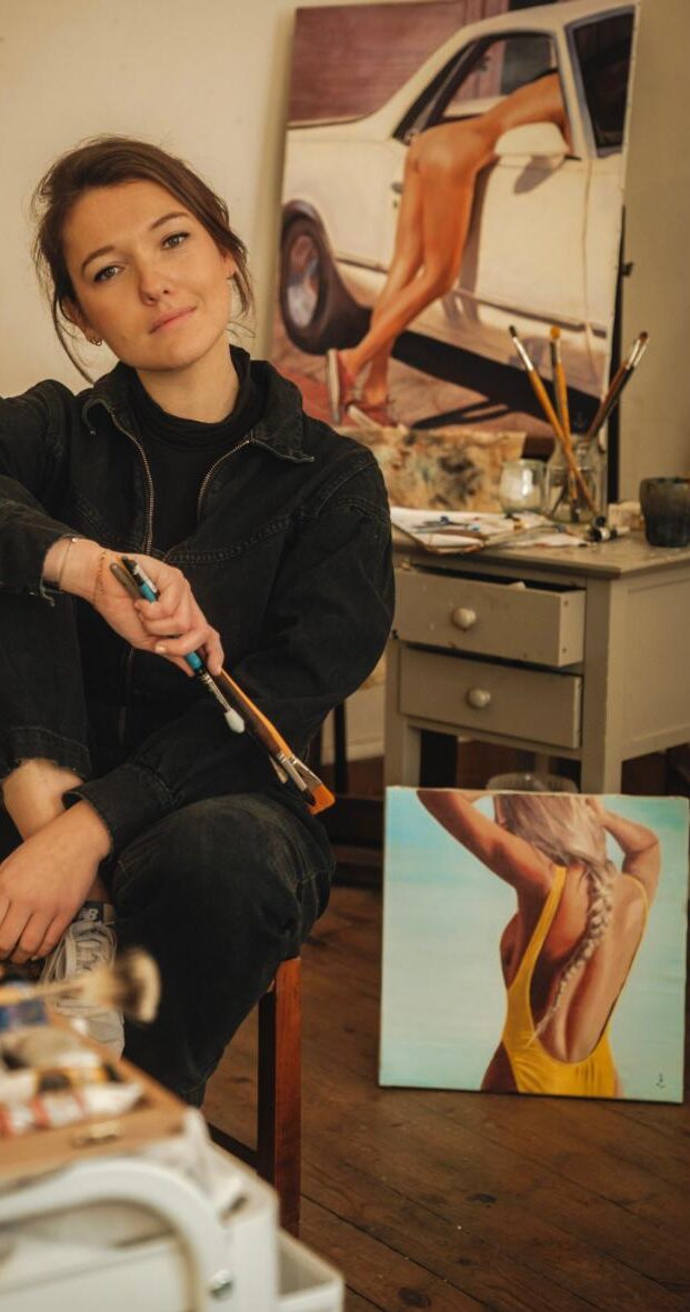 Une artiste peintre, jeune et dynamique, posant devant une de ses toiles dans son atelier