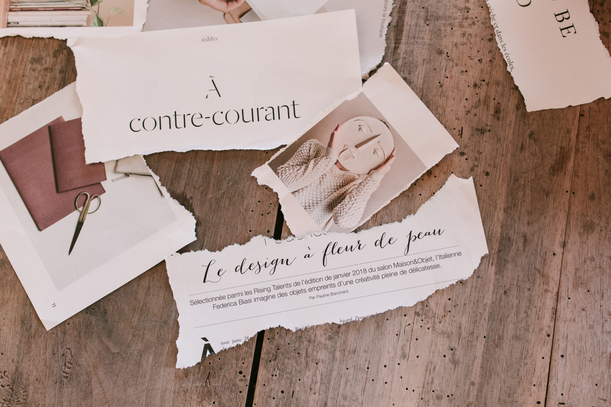 Coupures de magazine d'art éparpillées sur une table en bois brut
